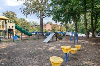 A playground with a green slide, a yellow and blue play structure, and yellow and blue swings.at Aspen at Lake Trail, Maryland